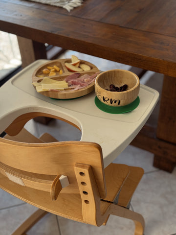 Bamboo plate and bowl set with strong suction base on a highchair, perfect for baby-led weaning and mess-free feeding.