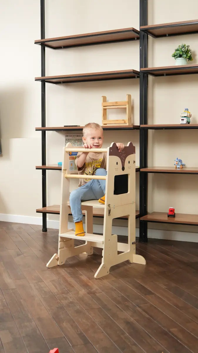 toddler smiling while sitting on a fox learning tower