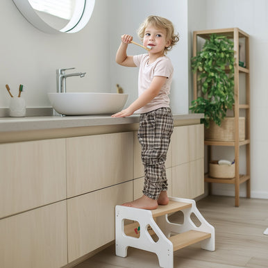 A toddler using a step stool for practicing tooth brushing 