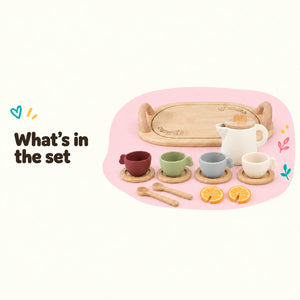 Silicone tea set pieces laid out: wooden tray, teapot, cups on saucers, spoons and lemon slices