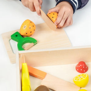 Wooden play pineapple being cut with a toy knife on a chopping board